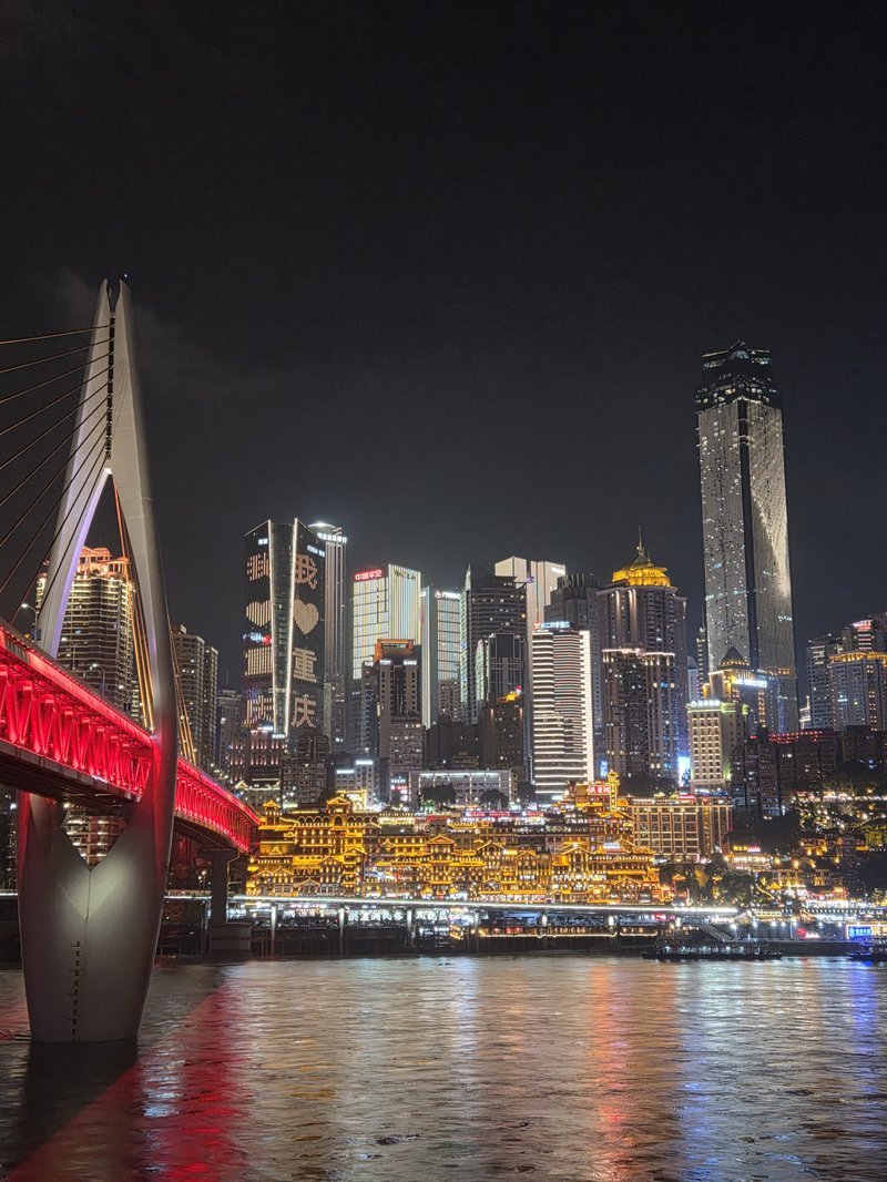 Ponte vermelha e luzes refletidas no rio em Chongqing