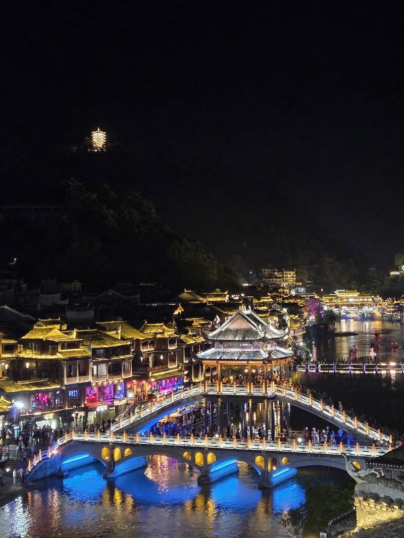 Fenghuang iluminada a noite refletida no rio