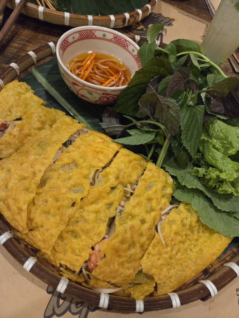 Bánh xèo no cesto de bambu com ervas frescas